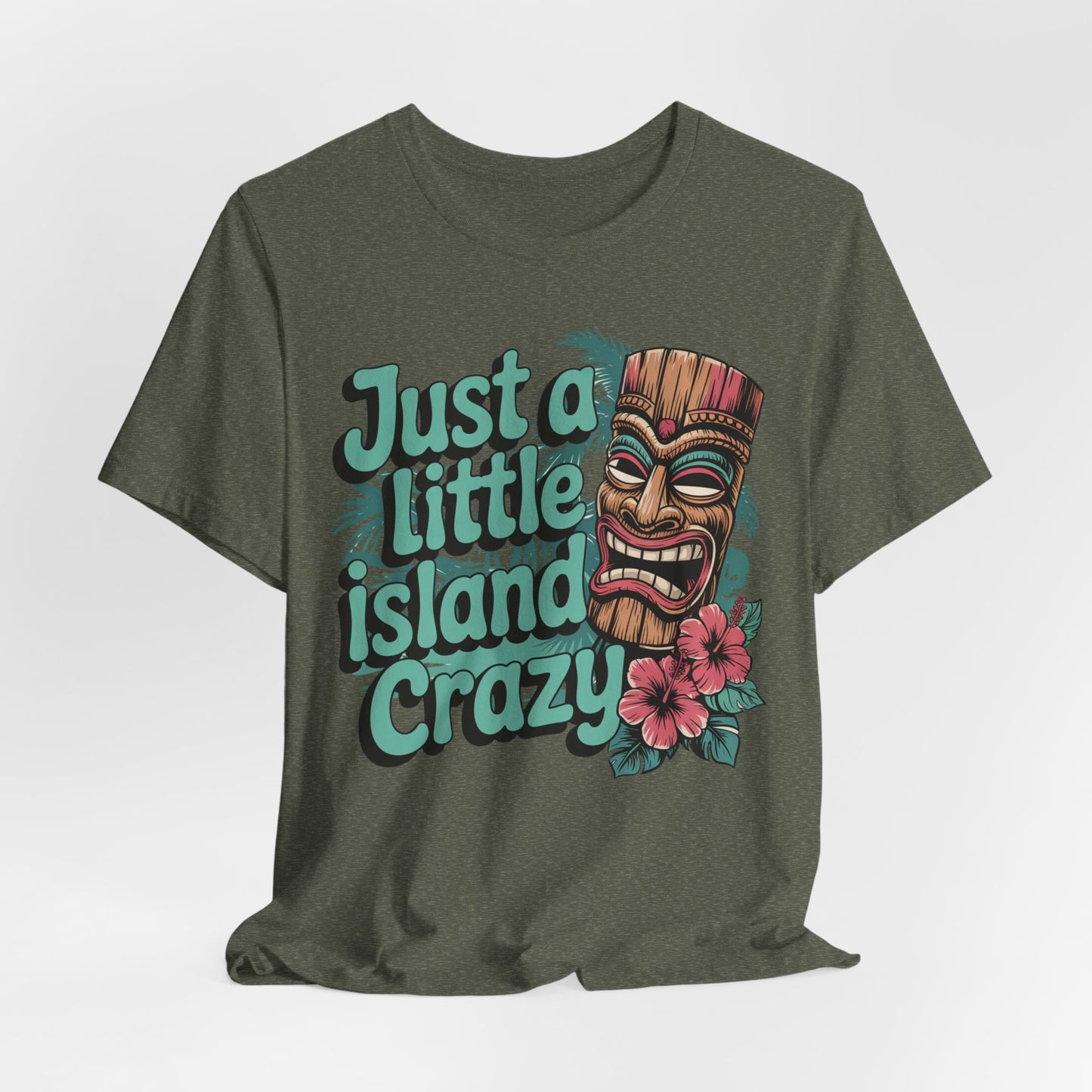The Tiki Island Crazy Unisex Tiki T-Shirt showcases a colorful tiki mask, pink hibiscus flowers, and the phrase Just a Little Island Crazy for fun tropical vibes—perfect for celebrating vibrant island culture.