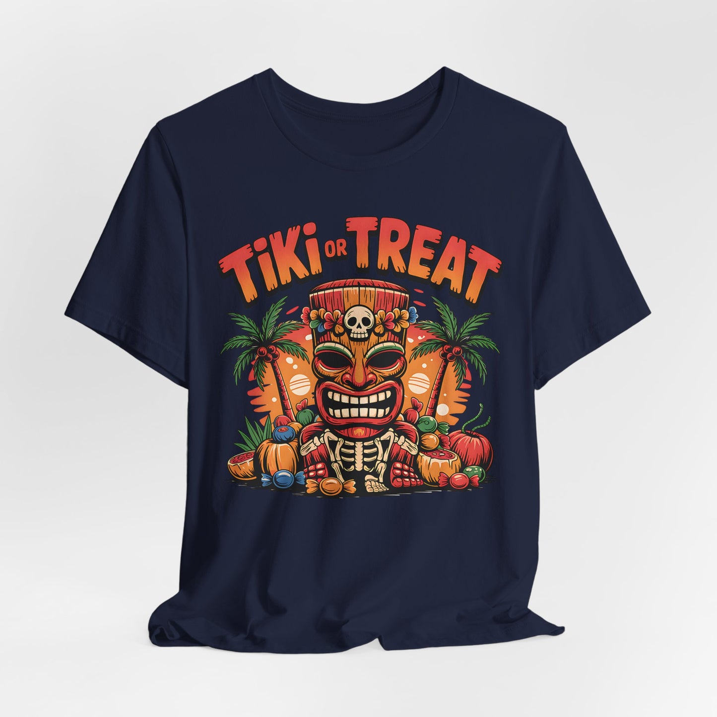 The Tiki or Treat Halloween Tiki T-Shirt - Unisex Jersey Short Sleeve Tee in navy features a vibrant tiki mask with skull, pumpkins, palm trees, and candy. “Tiki or Treat” stands out above the festive design for a perfect tropical Halloween vibe.