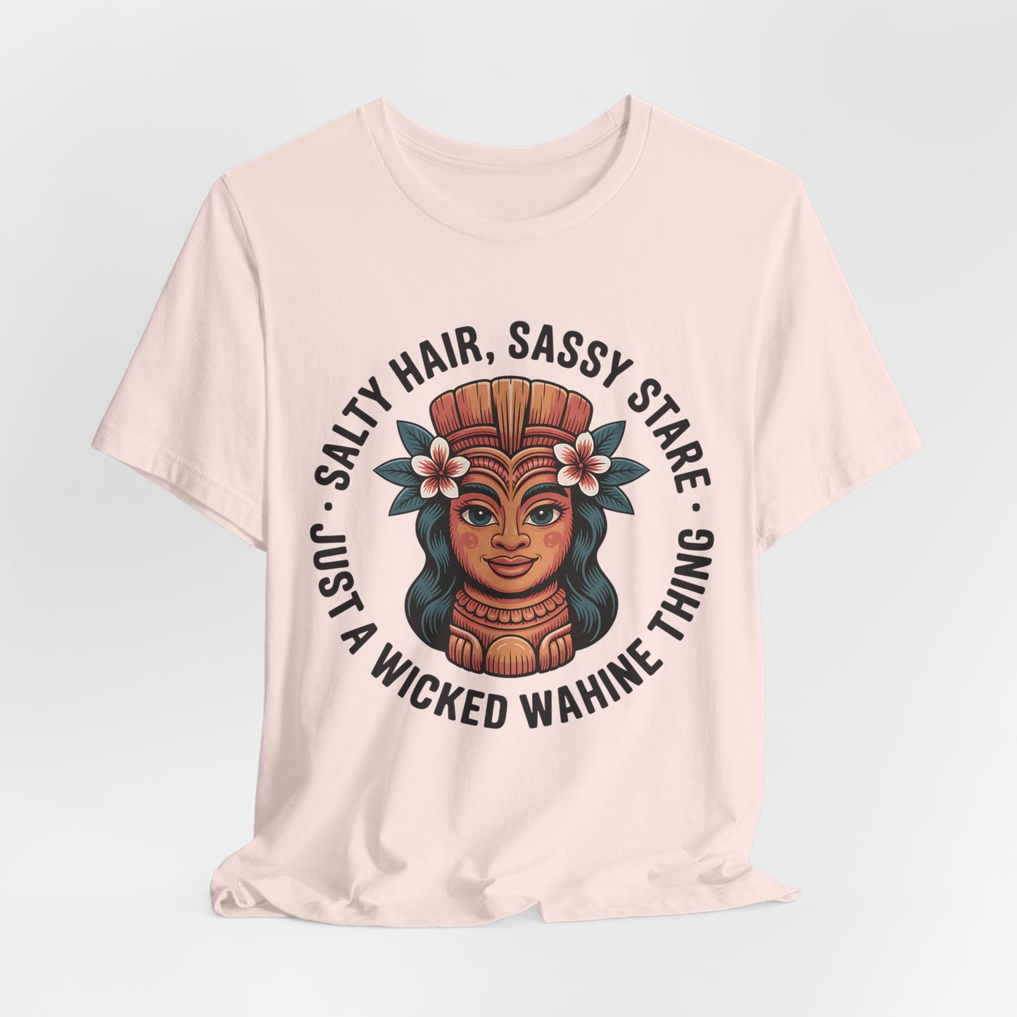 The Wicked Wahine Graphic T-Shirt - Salty Hair, Sassy Stare T-Shirt features a smiling woman with a floral headdress and the words Salty Hair, Sassy Stare. Ideal for nature lovers and beach trips—just a wicked wahine thing!.