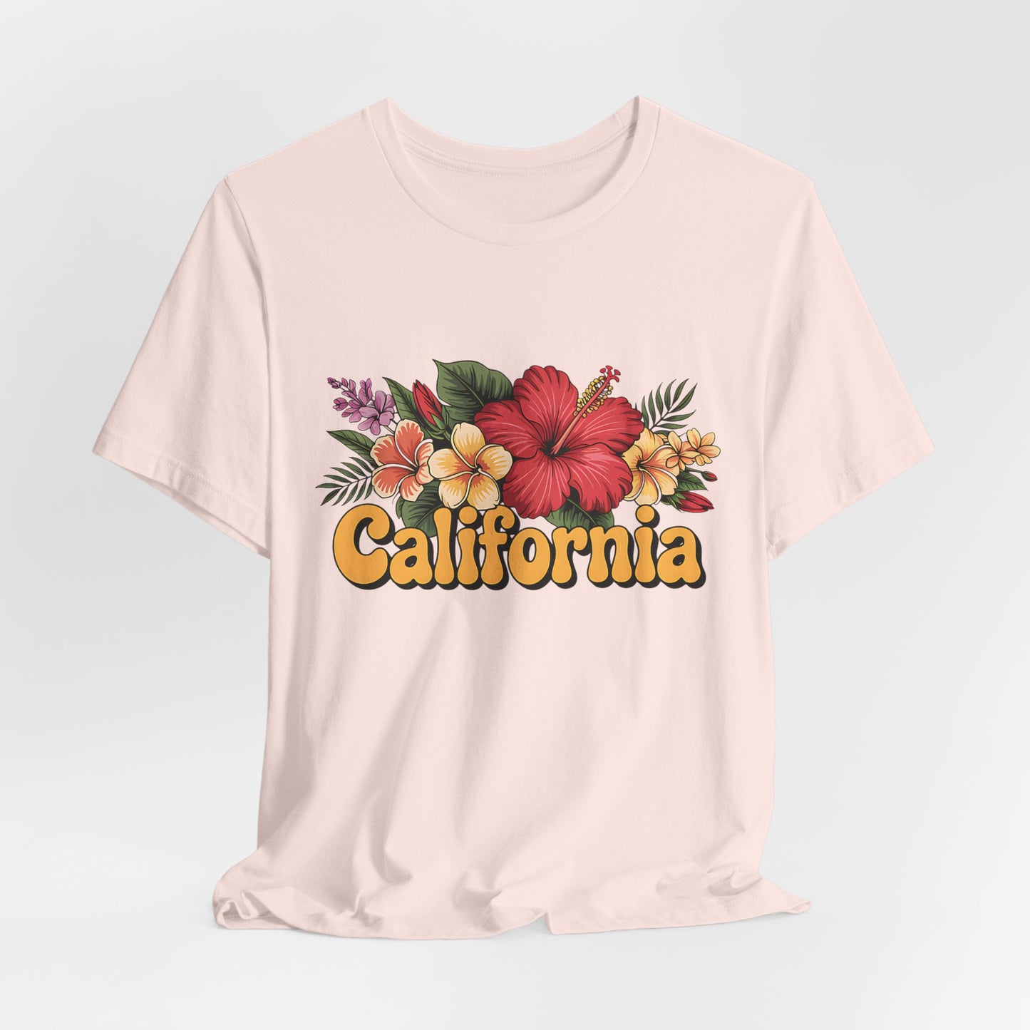 The California Floral Graphic T-Shirt features retro text and tropical flowers with green leaves, printed on a soft Unisex Jersey Short Sleeve Tee for summer vibes.