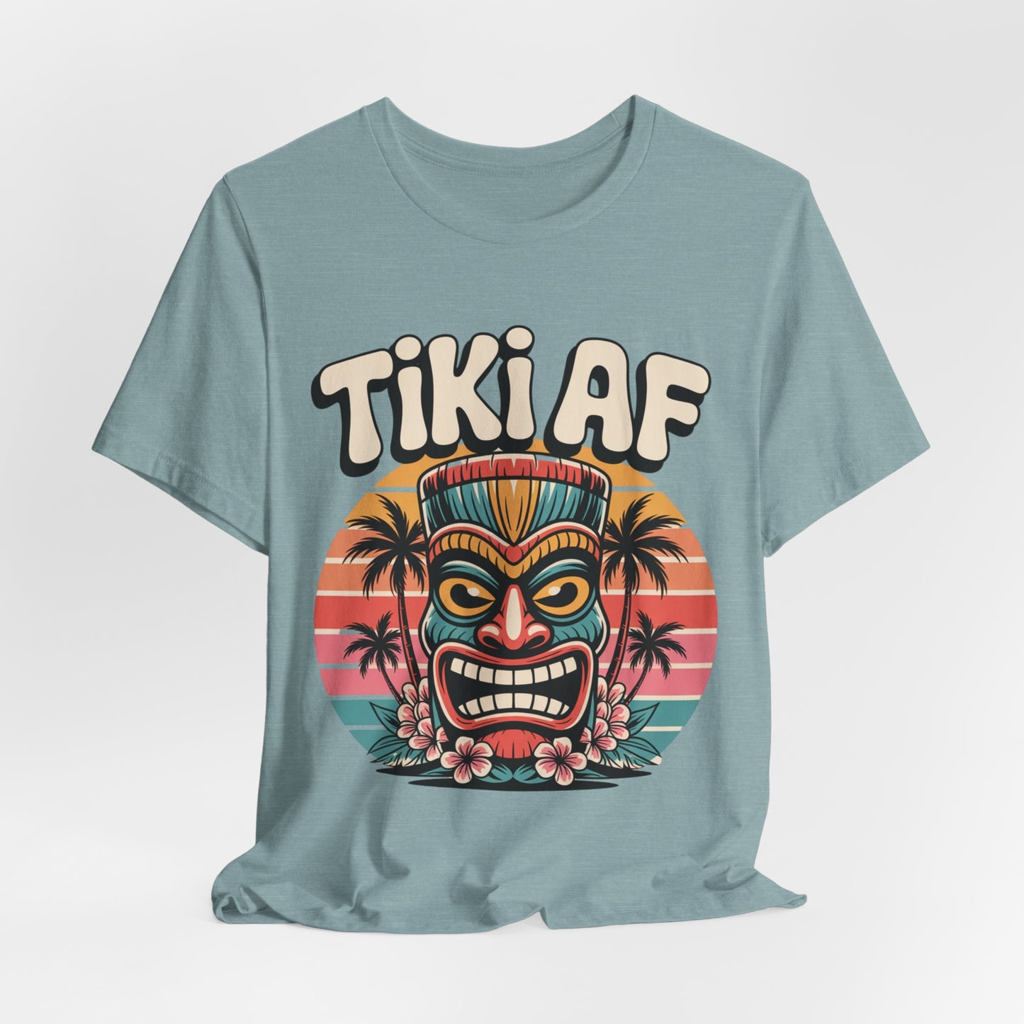 The Tiki AF Unisex Jersey Short Sleeve Tiki T-Shirt features a vibrant tiki face, hibiscus flowers, and palm trees at sunset with bold Tiki AF text—ideal for beach lovers seeking a fun, tropical vibe.