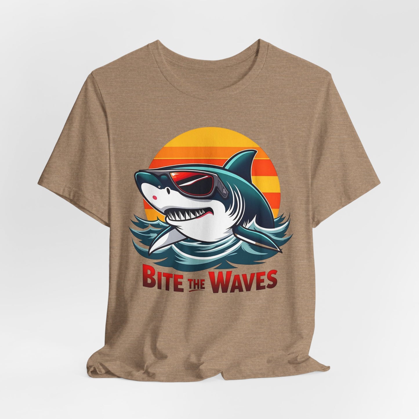 The Bite the Waves Shark T-Shirt is a cool unisex jersey featuring a cartoon shark in sunglasses with a sunset backdrop and bold BITE THE WAVES text. Perfect for summer fun and beach vibes.