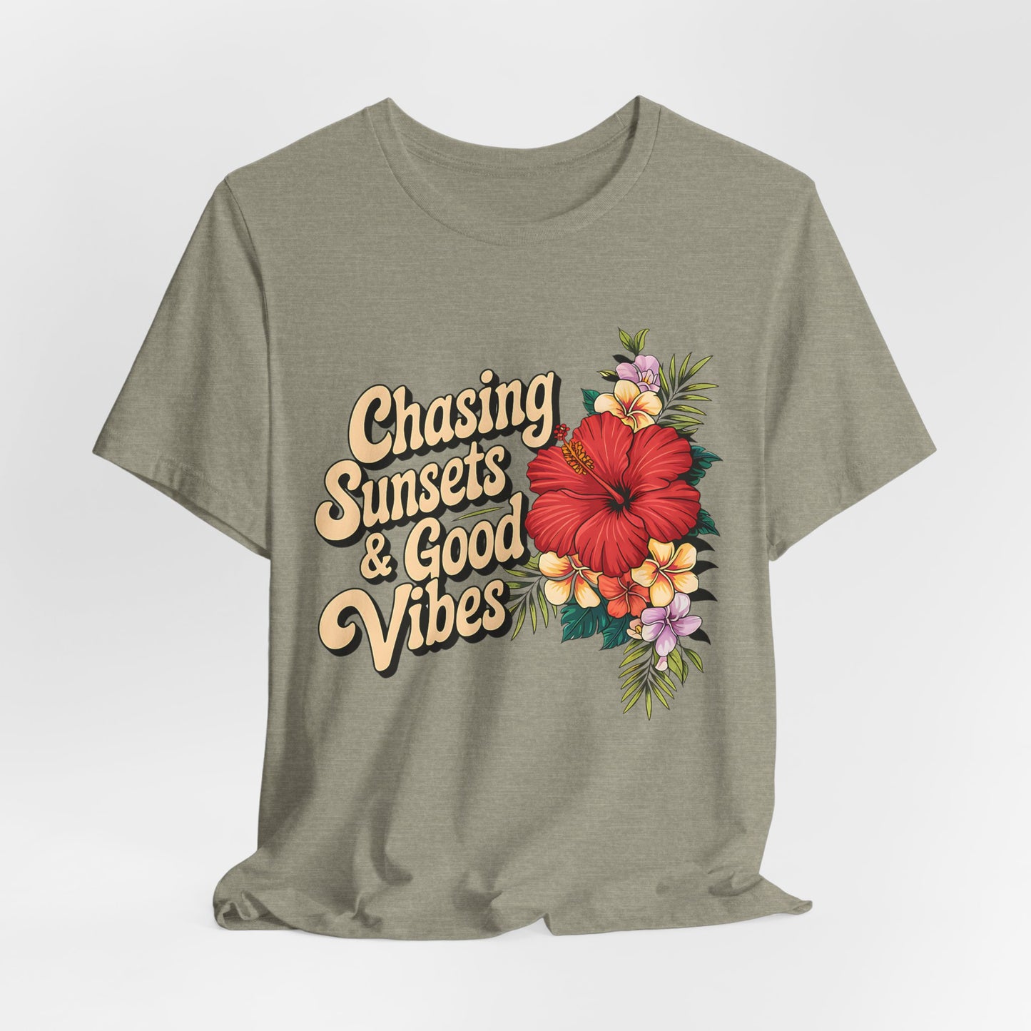 The Chasing Sunsets & Good Vibes Tee is an olive green unisex jersey short sleeve shirt for summer adventures, featuring retro text and a vibrant floral design with a red hibiscus plus yellow and purple flowers on the right side.