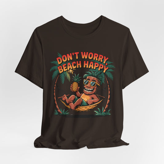 The Dont Worry Beach Happy Tiki T-Shirt is a relaxed unisex jersey tee featuring a colorful cartoon in sunglasses lounging in a hammock with a pineapple—ideal for beach lovers and tropical vibes. Text: DONT WORRY BEACH HAPPY.