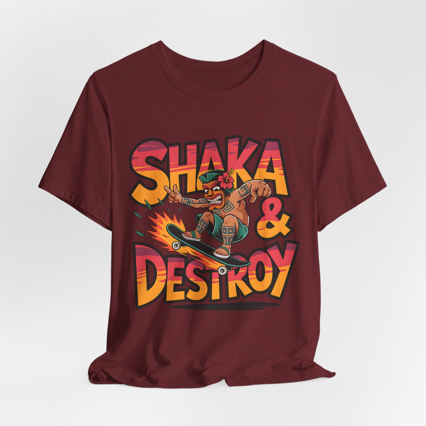 The Shaka & Destroy Graphic Tiki T-Shirt is a maroon unisex jersey tee featuring a vibrant cartoon skateboarder in a grass skirt and flower lei, with bold, colorful SHAKA & DESTROY text—perfect for skateboard enthusiasts.